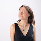 Smiling woman modeling ResQ safety necklace - stylish personal security jewelry for women's peace of mind and protection