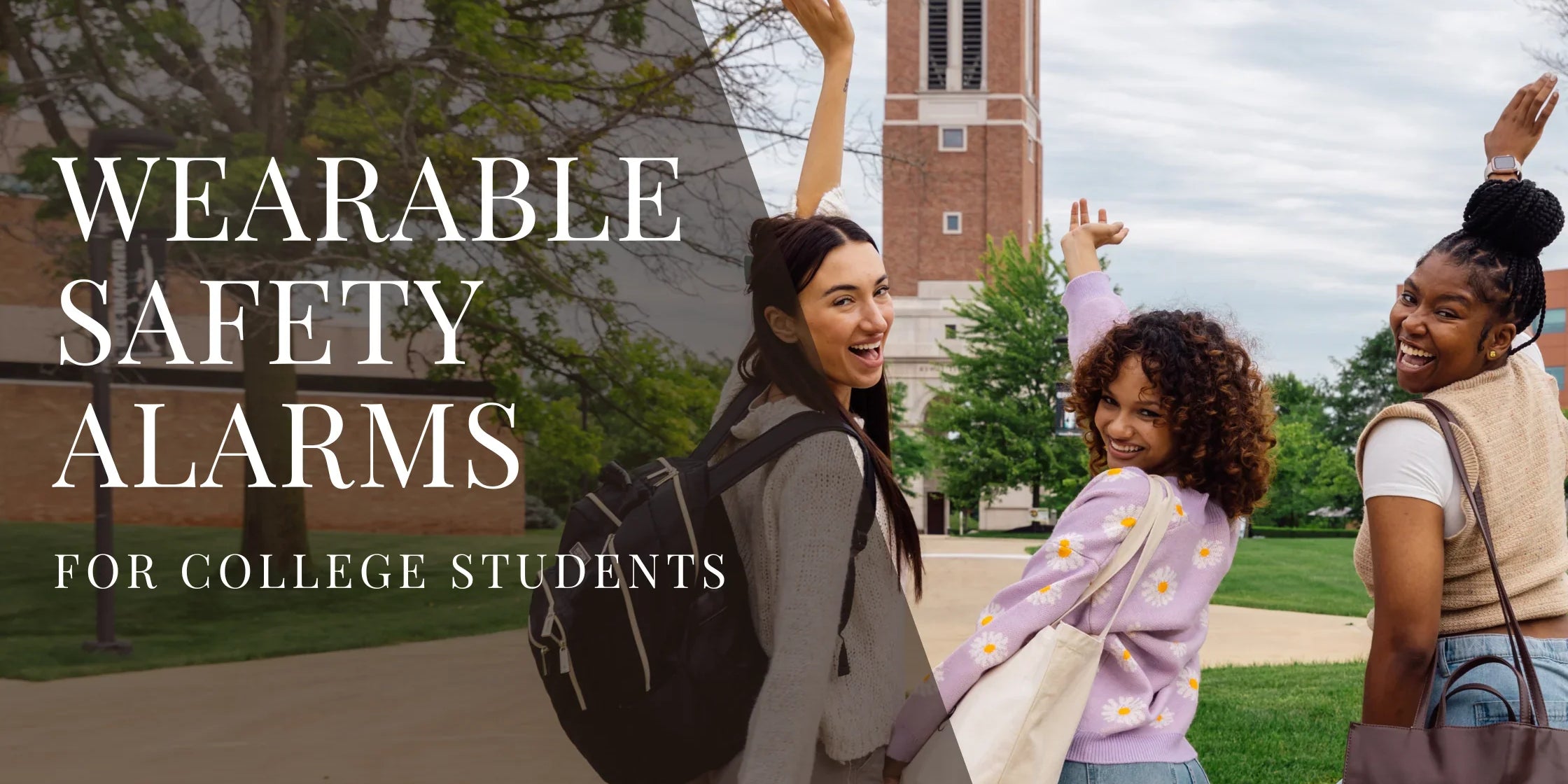 Three college students walk together on campus, smiling and raising their arms playfully, with a brick clock tower and green trees in the background.